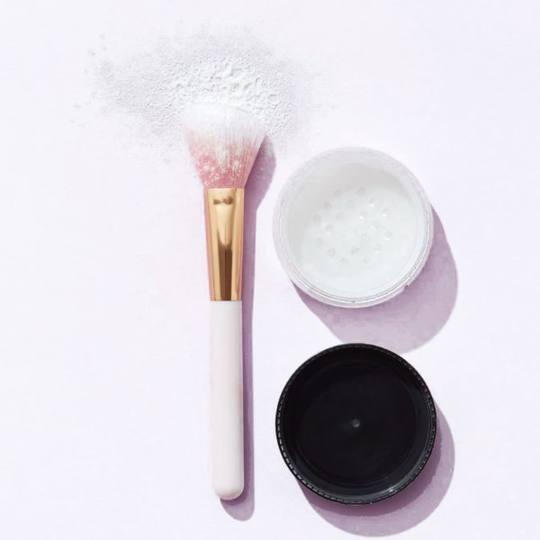 Powder brush and loose powder on lilac